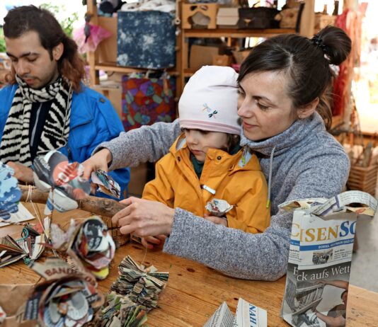 Dia Carrasco Soto und Christin Ferch mit Tochter Elsa basteln aus SachsenSonntagzeitungen Lampen, Taschen und Bl&uuml;ten. Foto: Andr&eacute; Kempner