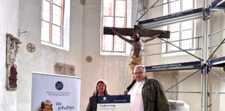 Angelika Dörrscheidt von der Deutschen Stiftung Denkmalschutz überreicht Pfarrer Matthias Taatz in der Kirche zu Brinnis den symbolischen Fördervertrag. Foto: Stephanie Bechert
