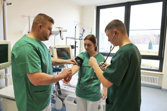 Ausbildung_im_SKH_Altscherbitz Der zentrale Praxisanleiter Philipp Teich (l.) zeigt Auszubildenden, wie man den Blutdruck misst. Foto: SKH Altscherbitz