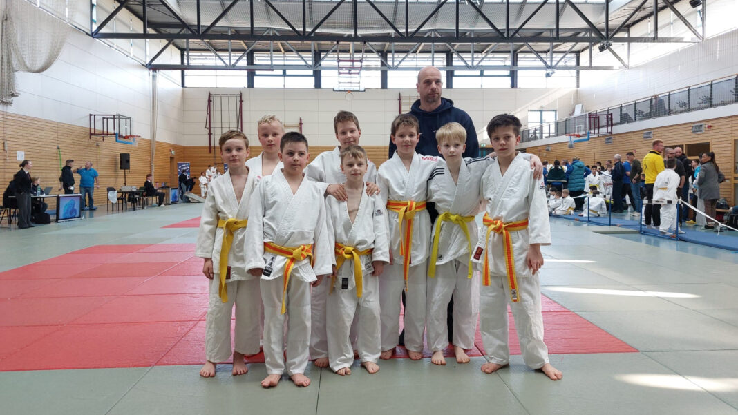 Judo-Bezirkseinzelmeisterschaft Gruppenbild Judoka im Judogi mit gelbem Gürtel mit Trainer.