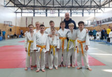 Gruppenbild Judoka im Judogi mit gelbem Gürtel mit Trainer.