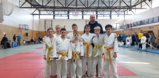 Gruppenbild Judoka im Judogi mit gelbem Gürtel mit Trainer.