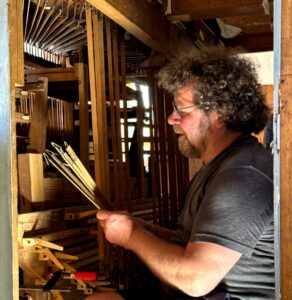 Matthias Sandig beim Einbau der vielen Abstrakte. Sie übertragen die Tastenbewegung ins Innere der Orgel und lassen schließlich die Orgelpfeife erklingen. Foto: Andreas Becher