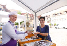 Der neue Grimmaer Oberbürgermeister Tino Kießig an der Essenausgabe mit einer Besucherin. Foto: Diakonie Leipziger Land