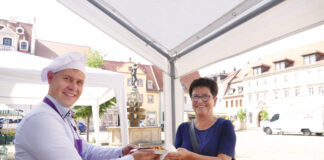 Der neue Grimmaer Oberbürgermeister Tino Kießig an der Essenausgabe mit einer Besucherin. Foto: Diakonie Leipziger Land