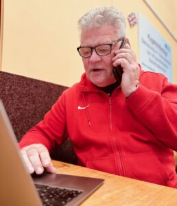Administratives gehört dazu: Sven Lang koordiniert mit Handy am Ohr und Laptop vor sich in der Trainingshalle Termine. Foto: Lars Preußer