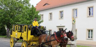 Die Postkutsche neben der M&uuml;gelner Postmeilens&auml;ule im Mai 2025. Zum Jubil&auml;umsfest am 3. Mai sollen vier der &bdquo;Gelben Wagen&ldquo; in M&uuml;geln zusammentreffen. Foto: Jan Seelig