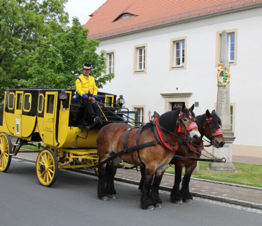 Die Postkutsche neben der M&uuml;gelner Postmeilens&auml;ule im Mai 2025. Zum Jubil&auml;umsfest am 3. Mai sollen vier der &bdquo;Gelben Wagen&ldquo; in M&uuml;geln zusammentreffen. Foto: Jan Seelig