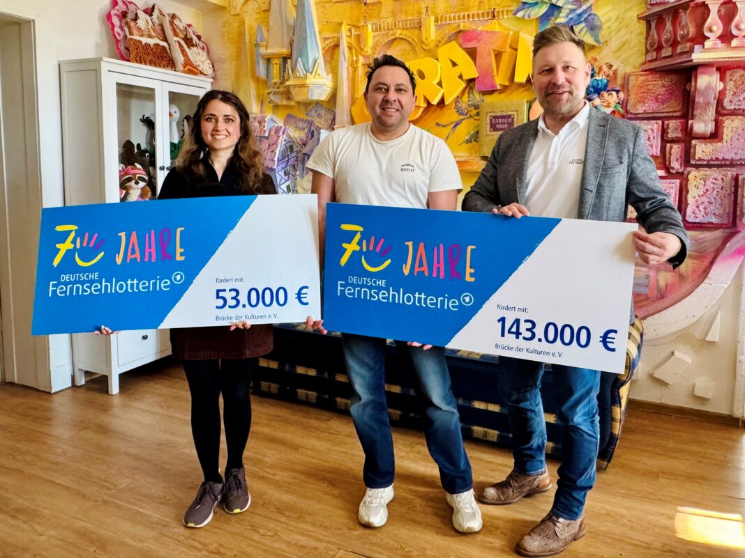 Zwei F&ouml;rderschecks hatte Stephan Masch von der Deutschen Fernsehlotterie beim Besuch in Leipzig dabei - sehr zur Freude von Diana Lorenz und Mikhail Vachtchenko vom Integrationsverein Leipzig-Br&uuml;cke. Foto: Max Th&uuml;mmel