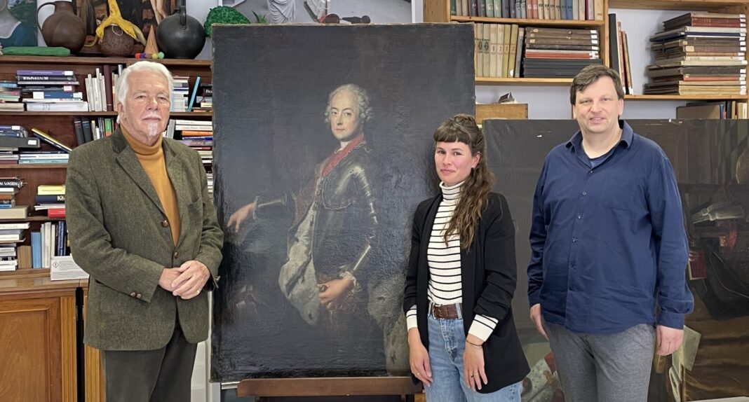 20260504_Restitution_an_Familien_von_Seckendorff v.l.: Rainer Graf von Seckendorff Marianne Lose, Provenienzforscherin, Dr. Benjamin Spira, stellvertretender Direktor der Altenburger Museen, neben der Kopie nach Antoine Pesne mit dem Porträt von Karl Alexander von Lothringen. Foto: Lindenau-Museum Altenburg/Julia Wiehenstroth