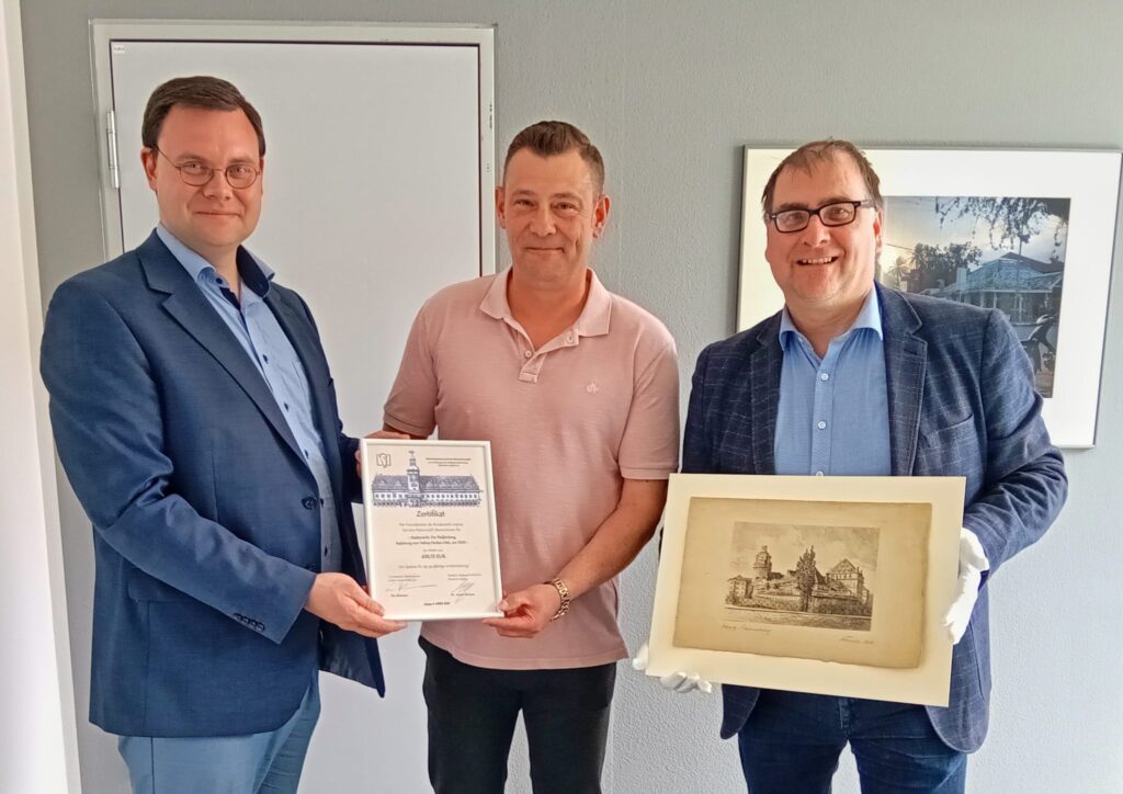 Heiko Stehr (m.) vom Freundeskreis der Bundeswehr in Leipzig hat eine eine Patenschaft f&uuml;r eine historische Grafik des Stadtgeschichtlichen Museums erworben. Er erh&auml;lt daf&uuml;r ein Paten-Zertifikat von Eric Buchmann. Dr. Anselm Hartinger (r.) h&auml;lt die Radierung "Die Plei&szlig;enburg" von Helma Fischer-Oels in der Hand, die restauriert wurde mit Hilfe der Patenschaft. Foto: Katja Etzold