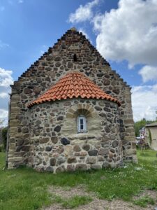 Rundapsis aus unverputztem Feldstein mit kleinem romanischen Fenster: An der Ostseite der Benndorfer Kirche zeigt sich besonders gut ihr hohes Alter. Foto: Nannette Hoffmann