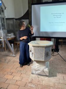 Steinrestauratorin Birgit Mühler erläutert beim Werkstattabend die Restaurierung des historischen Taufsteins von Laue. Foto: Nannette Hoffmann