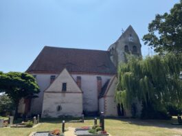 Die Kirche in K&ouml;lsa liegt ruhig neben dem Dorfteich. Auff&auml;llig ist ihr massiger runder Wehrturm. Foto: Nannette Hoffmann